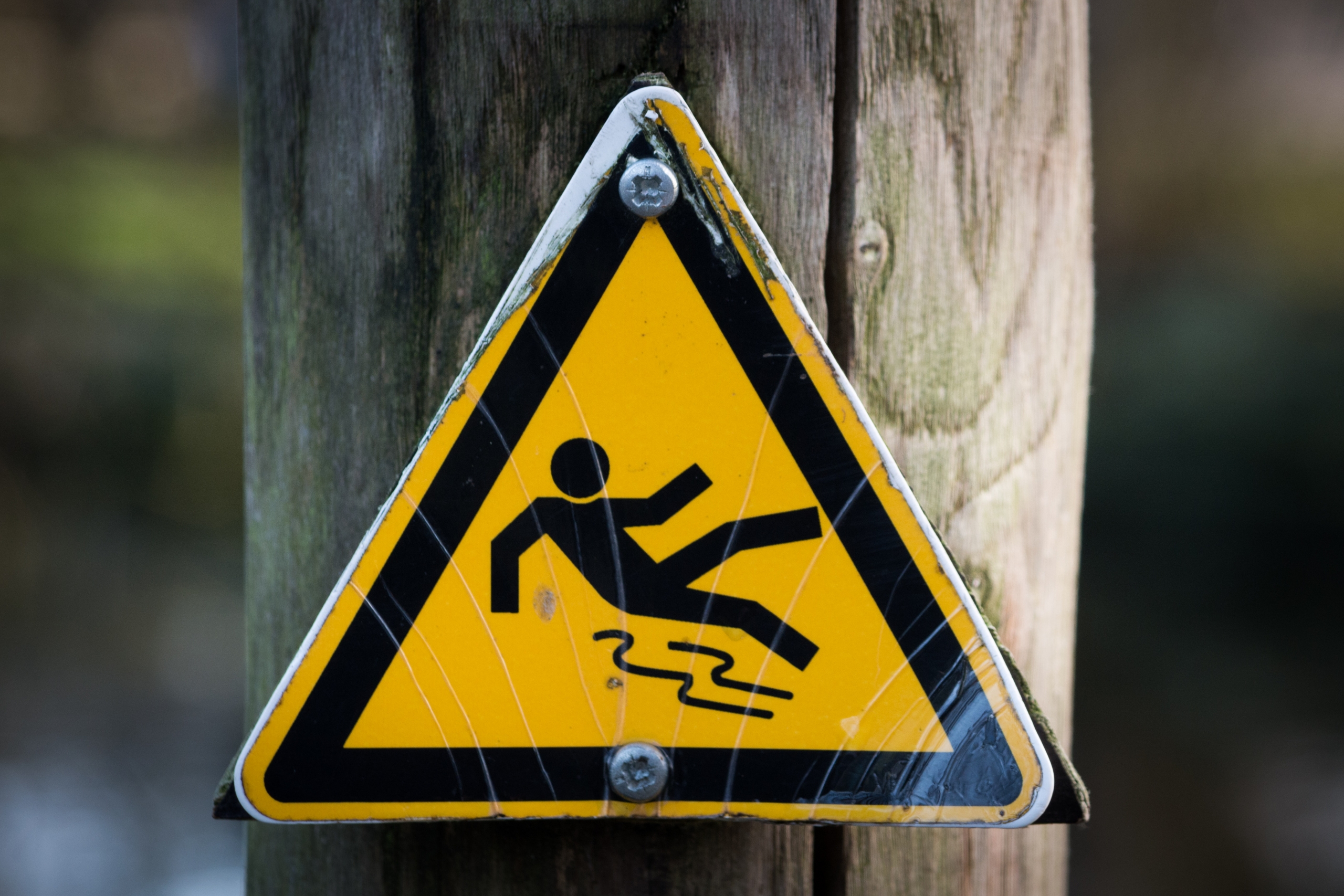 yellow and black danger sign with a man slipping over on it